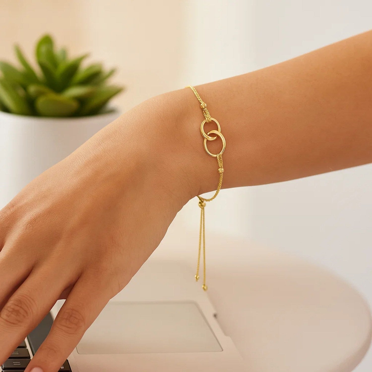 14k yellow gold adjustable lariat bracelet featuring entwined rings and a modern chain design for elegant sophistication.