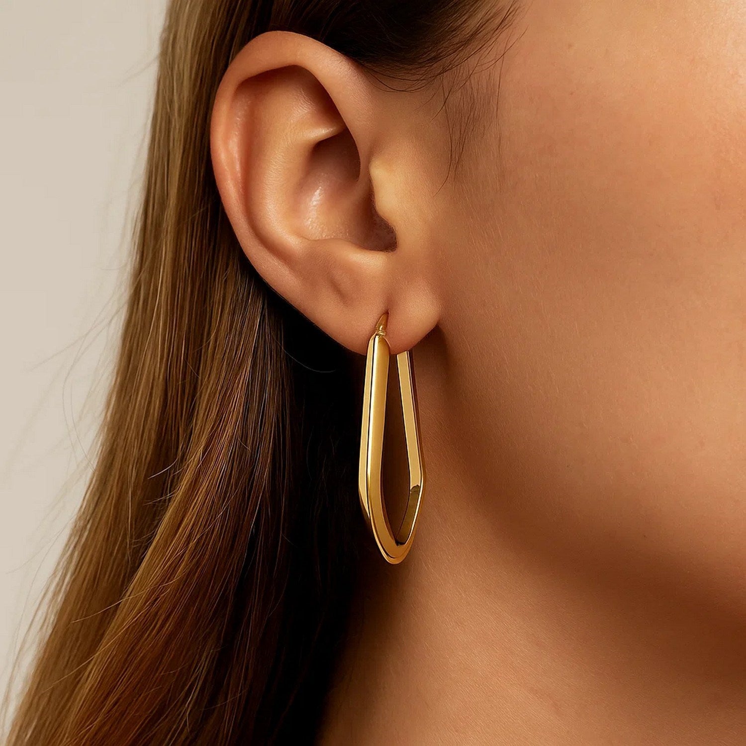 Polished 10K yellow gold geometric oval hoop earrings, showcasing modern elegance and refined craftsmanship.