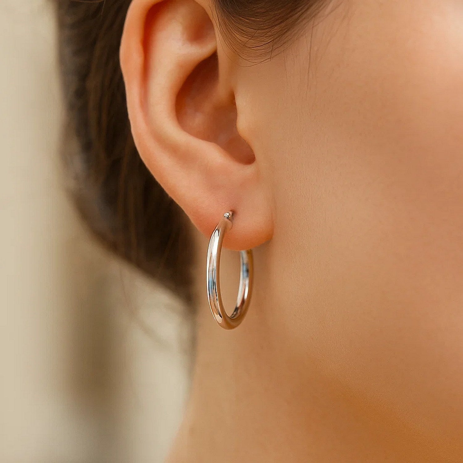 Sterling silver polished hoop earrings with rhodium plating, showcasing a modern design and elegant shine.