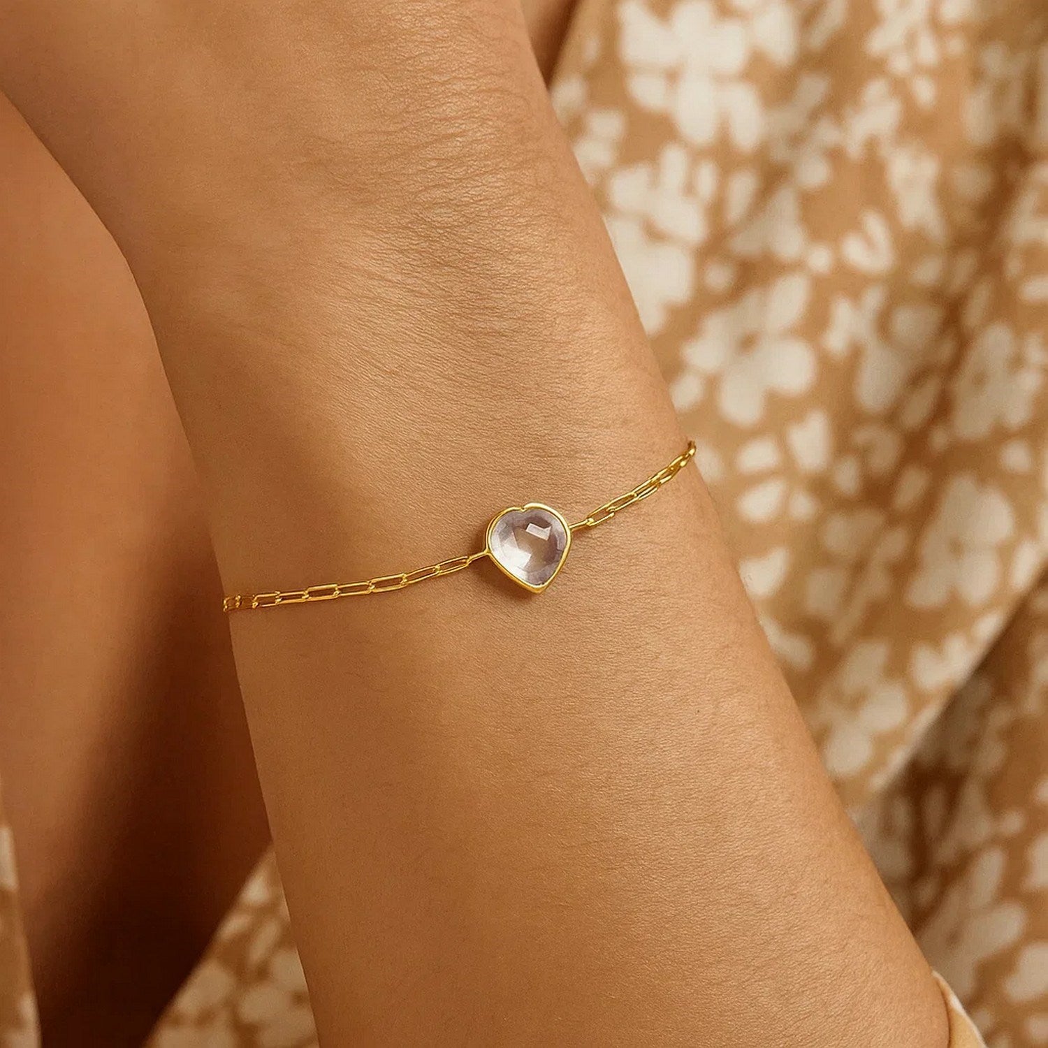 14k yellow gold heart bracelet featuring white topaz in a classic bezel setting with an elegant chain design.