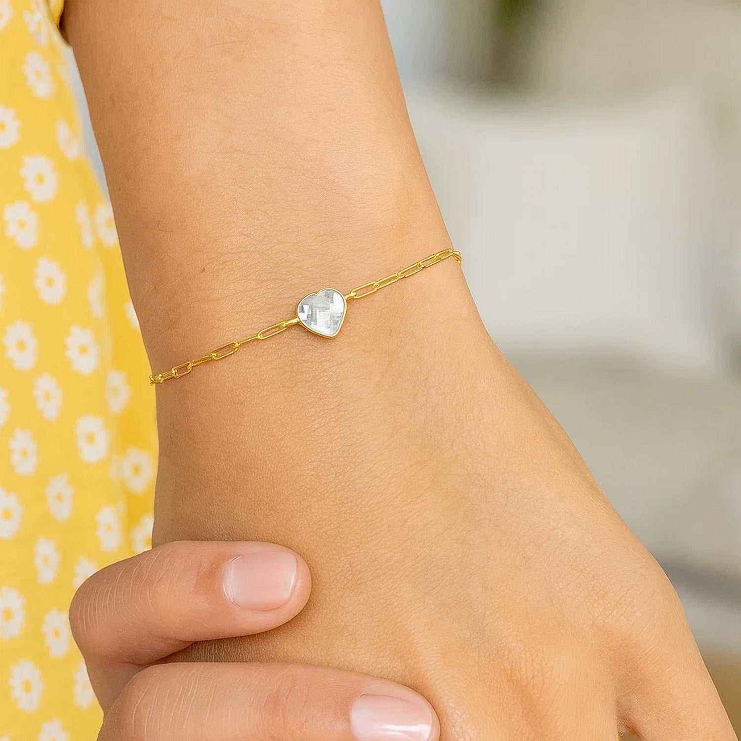 14K yellow gold heart bracelet featuring white topaz in a classic bezel setting with elegant chain design.