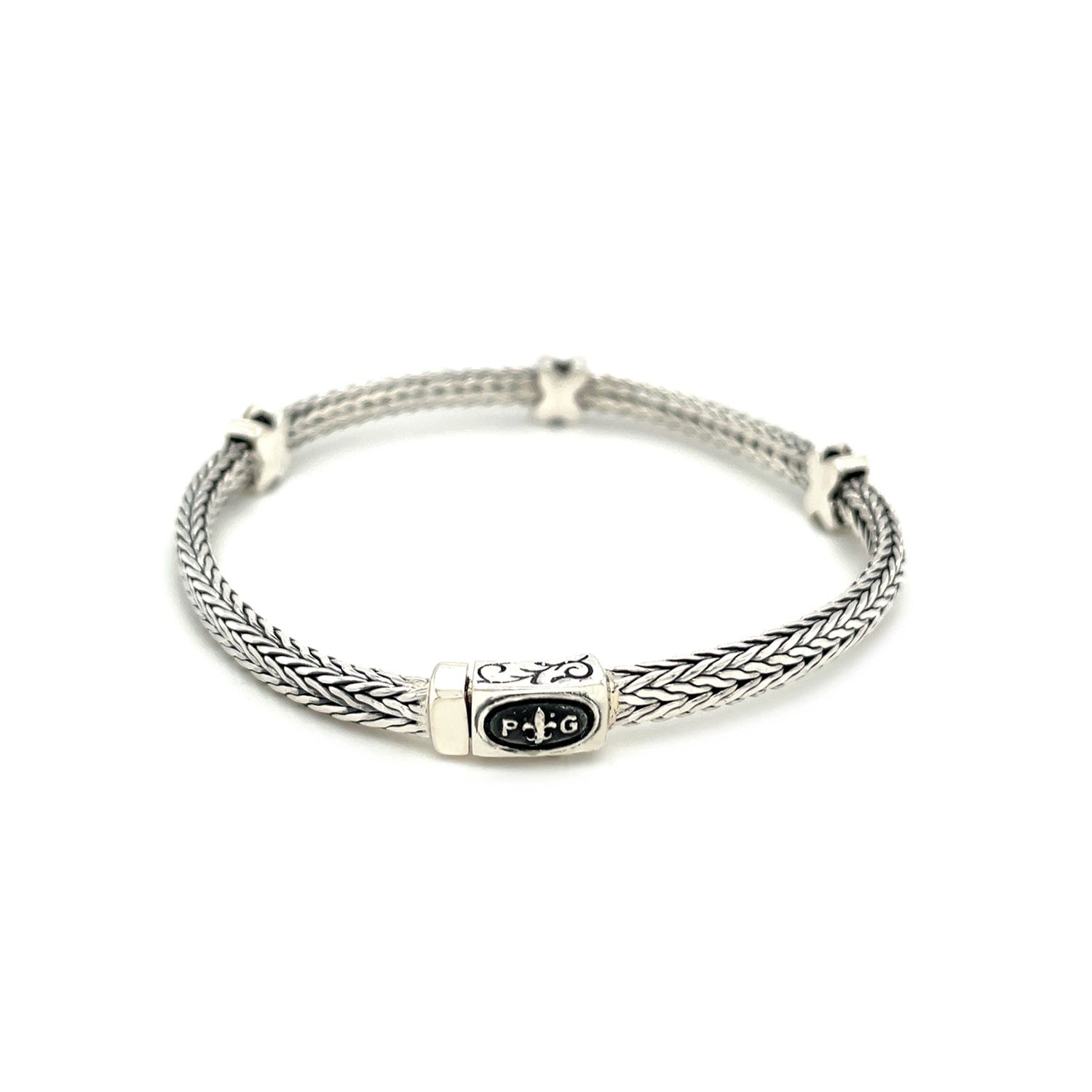 Woven rope bracelet in sterling silver with black sapphire X accents, showcasing modern luxury craftsmanship.