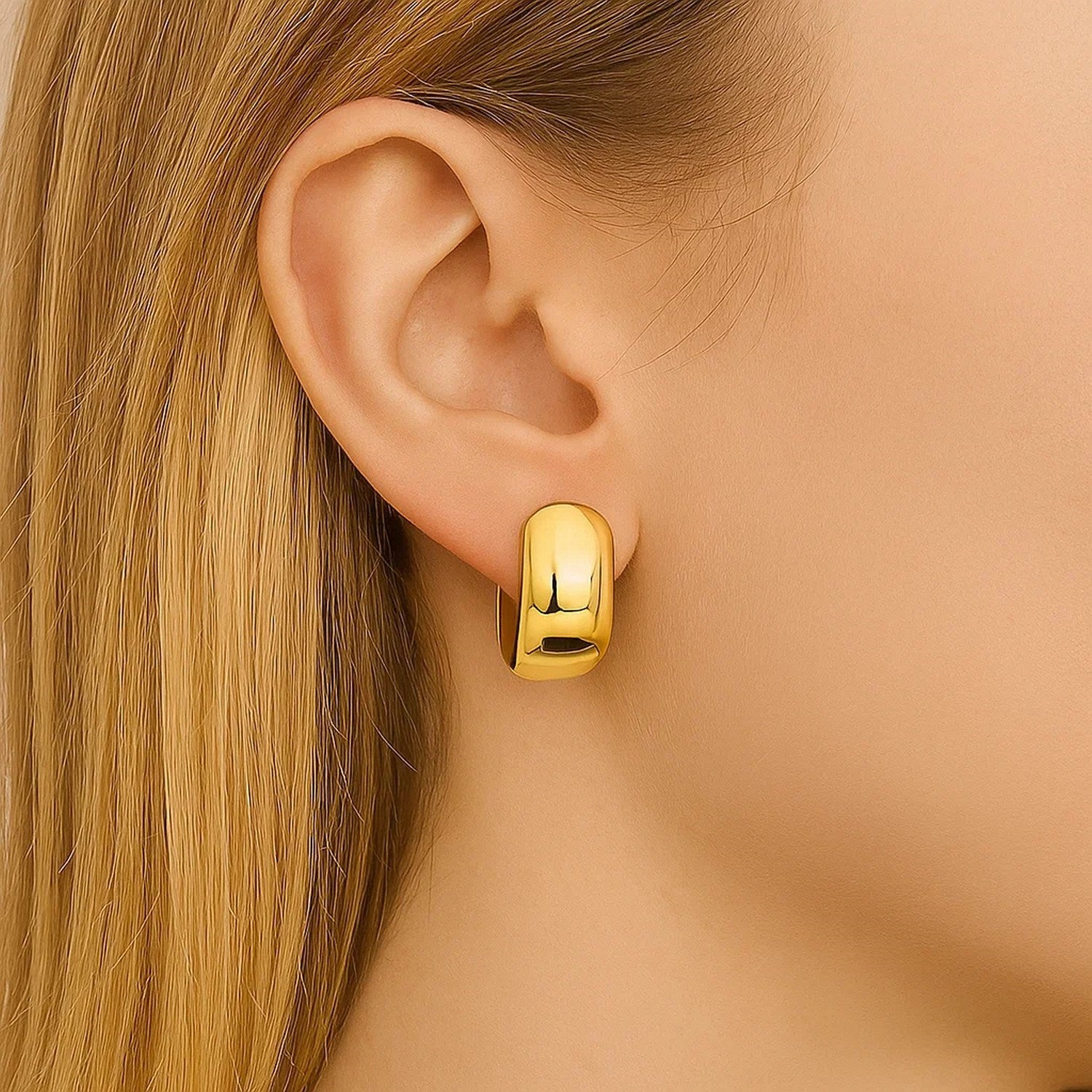 14K yellow gold polished huggie hoop earrings with a modern oval design, perfect for elegant everyday wear.