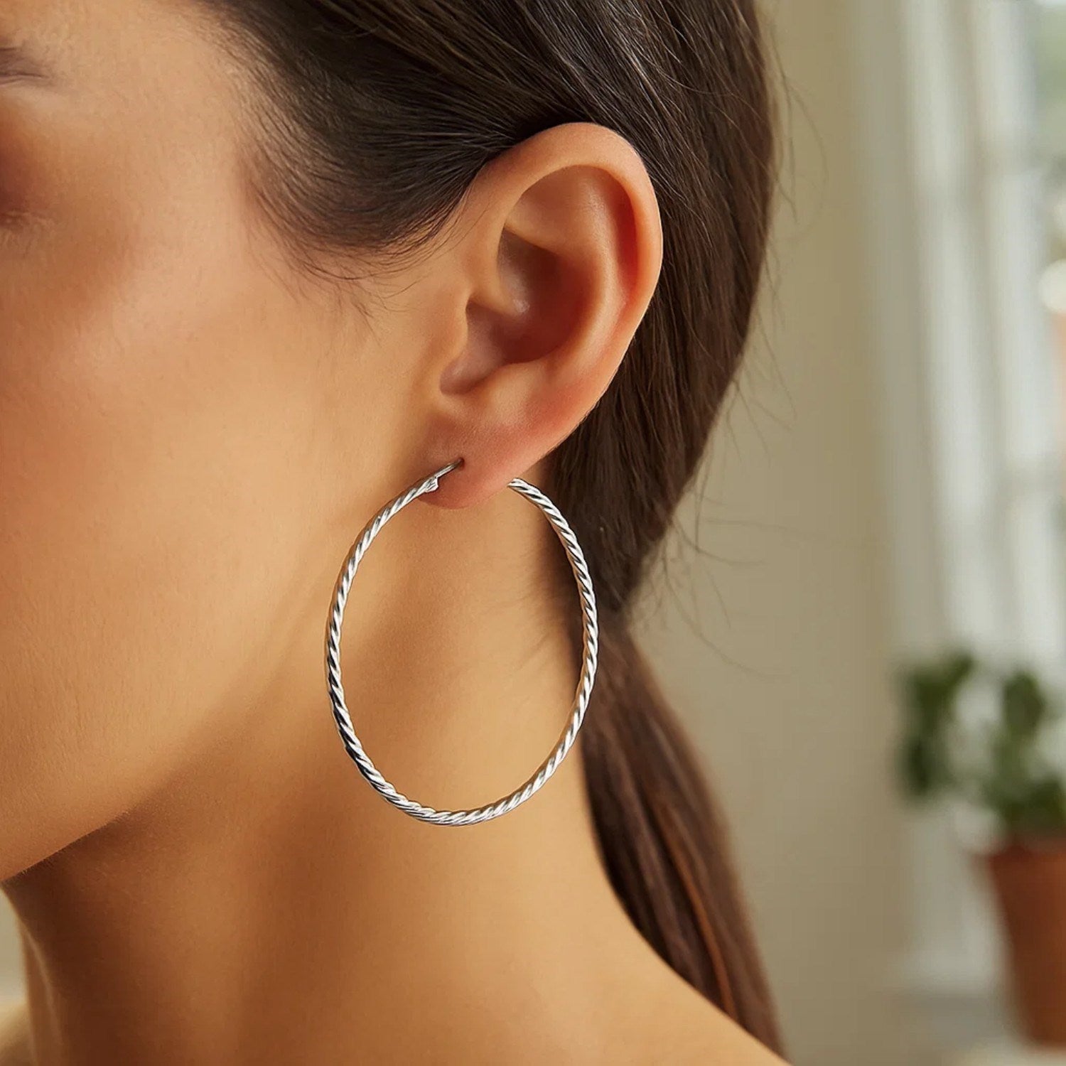 Sterling silver twist textured hoop earrings, elegantly designed for a luxurious statement.