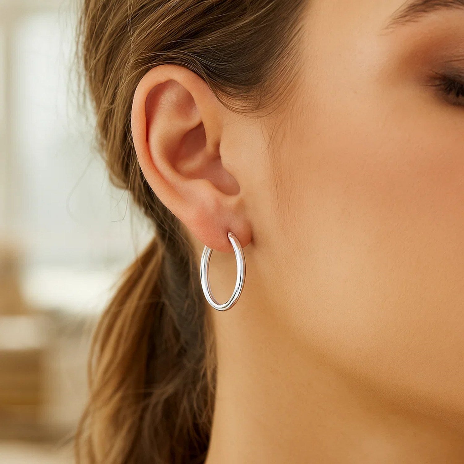 Sterling silver polished hoop earrings, rhodium plated, modern design, showcasing elegance and timeless style.