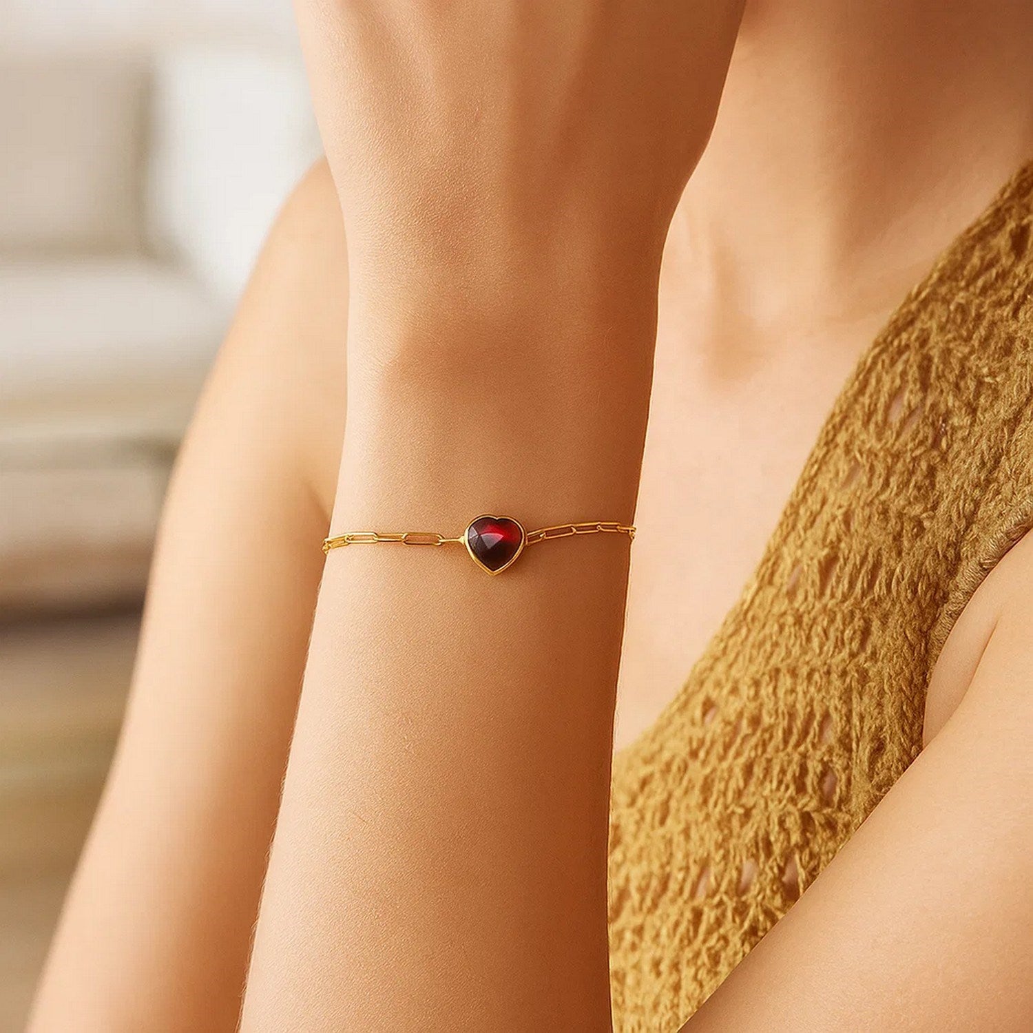 Elegant 14k yellow gold bracelet featuring a heart-shaped garnet on a delicate chain, perfect for luxury occasions.