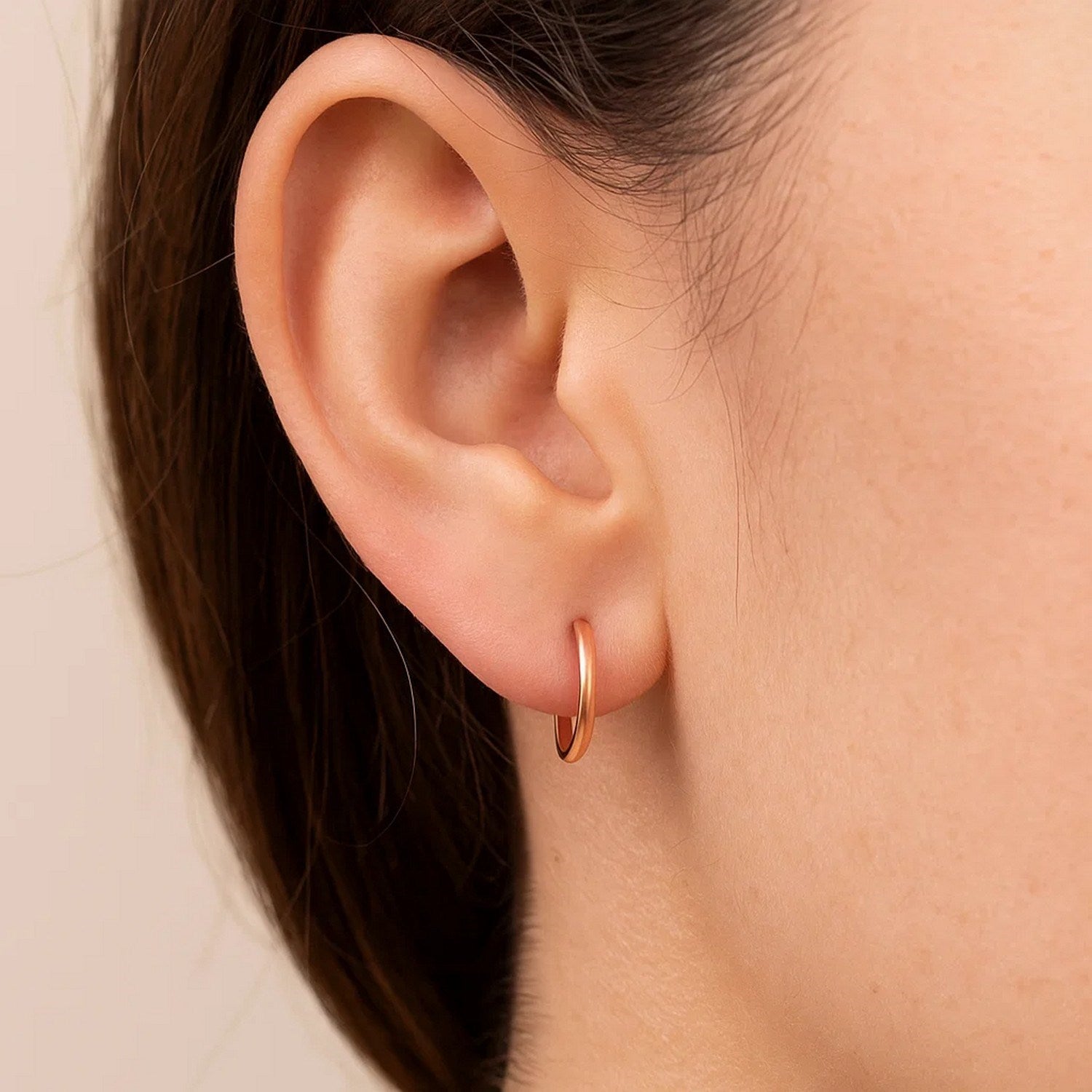 14k rose gold polished round hoop earrings showcasing a modern design with a sleek, luxurious finish.