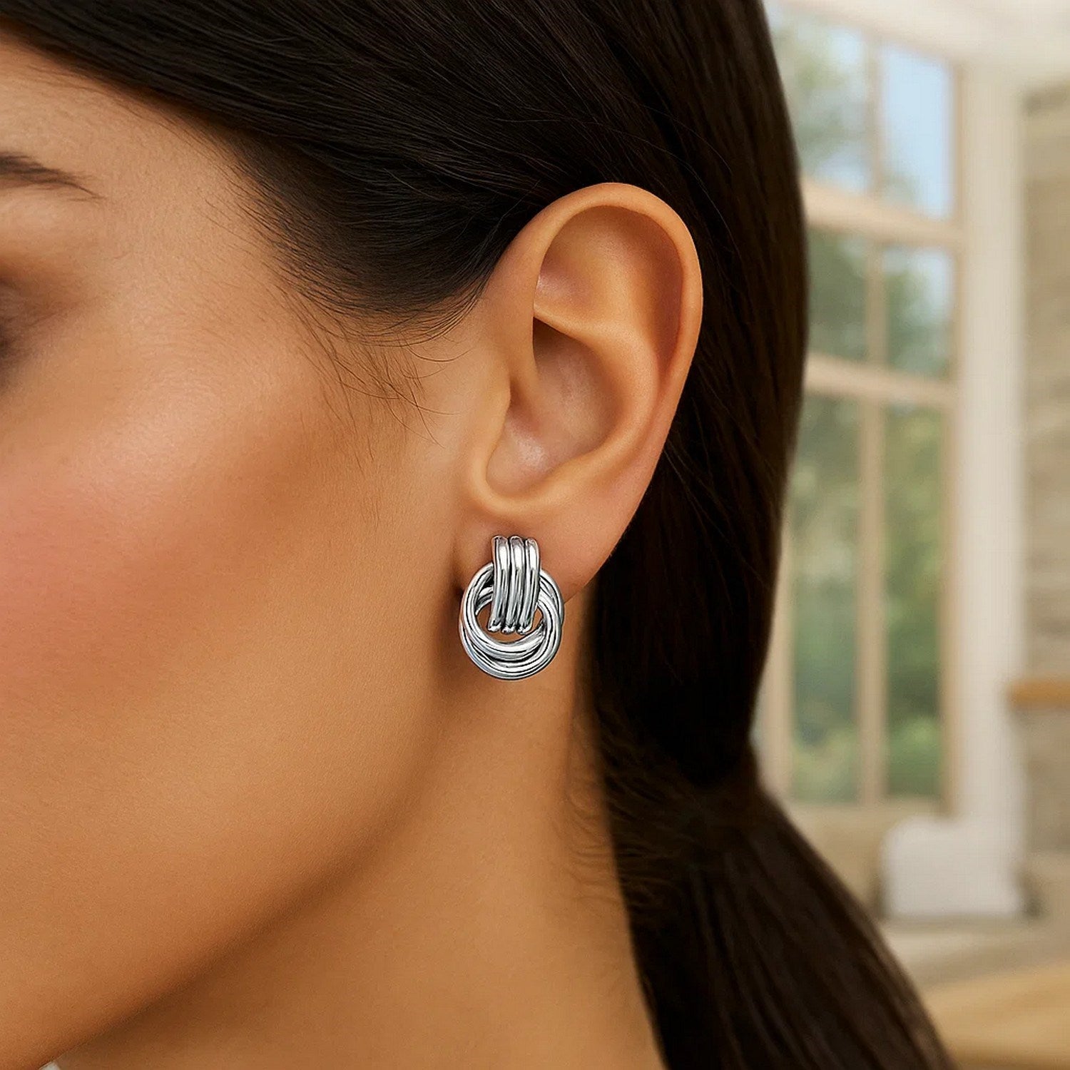 Polished sterling silver love knot earrings featuring interlocking rings in a modern design, perfect for luxury elegance.