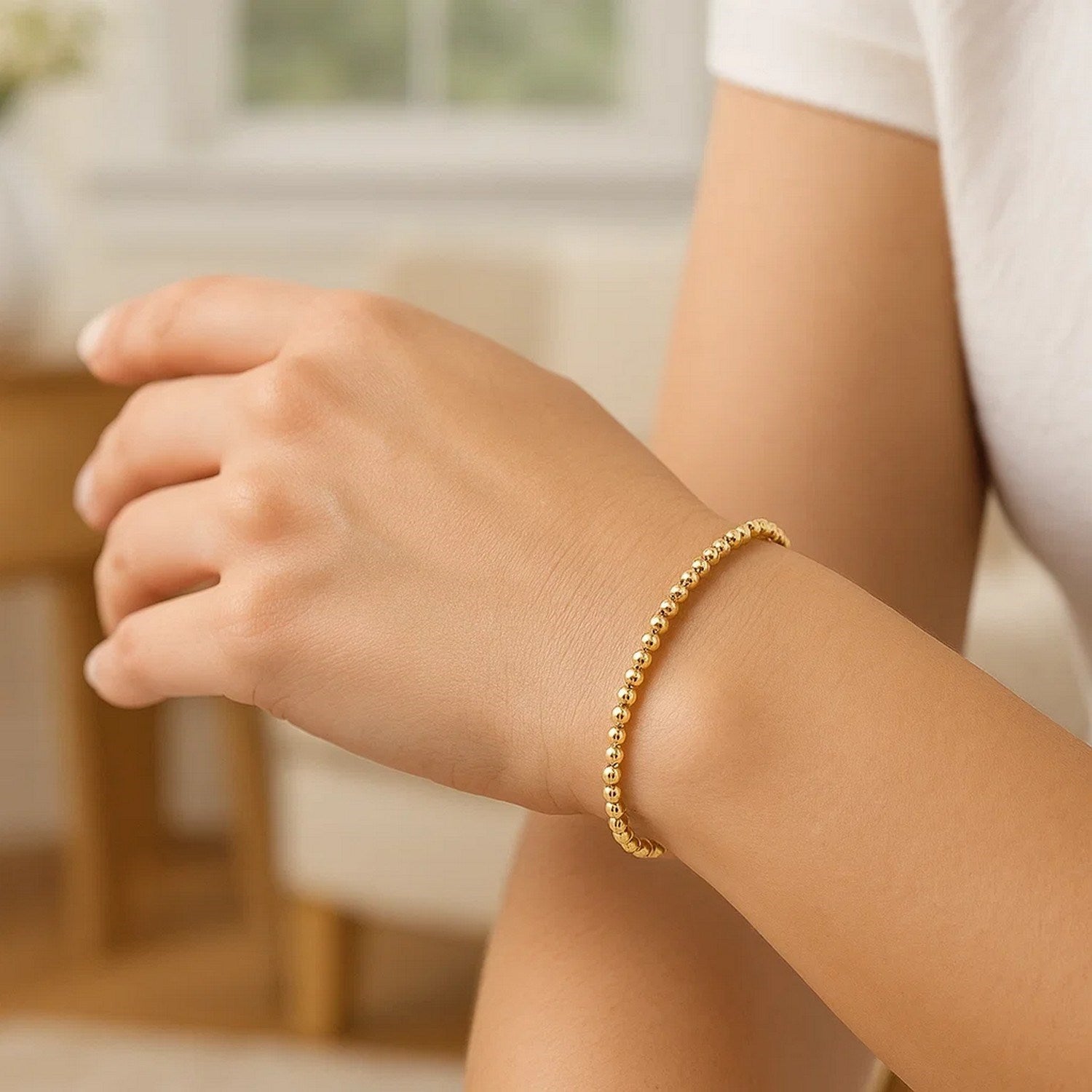 Elegant 14k yellow gold stretch bracelet with moon cut beads and diamond stud accents, showcasing refined luxury.