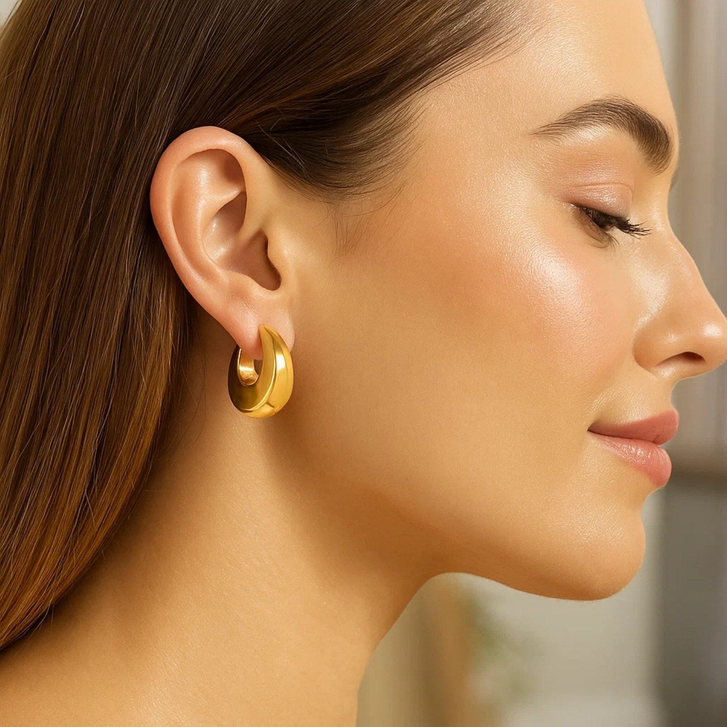Large tapered hoop earrings in 14k yellow gold, showcasing a modern design for a luxurious statement.