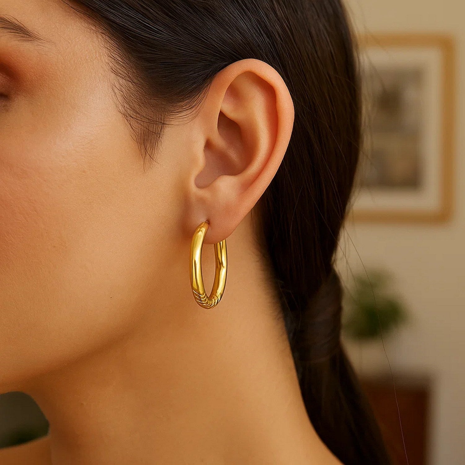 Polished 14k yellow gold large hoop earrings showcasing a modern design and luxurious shine.