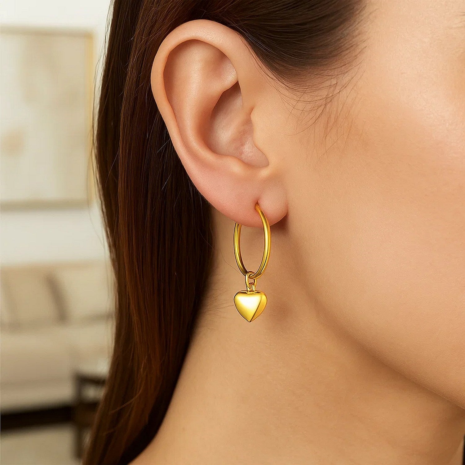 14k yellow gold hoop earrings featuring a dangling puffed heart for a modern, elegant touch.