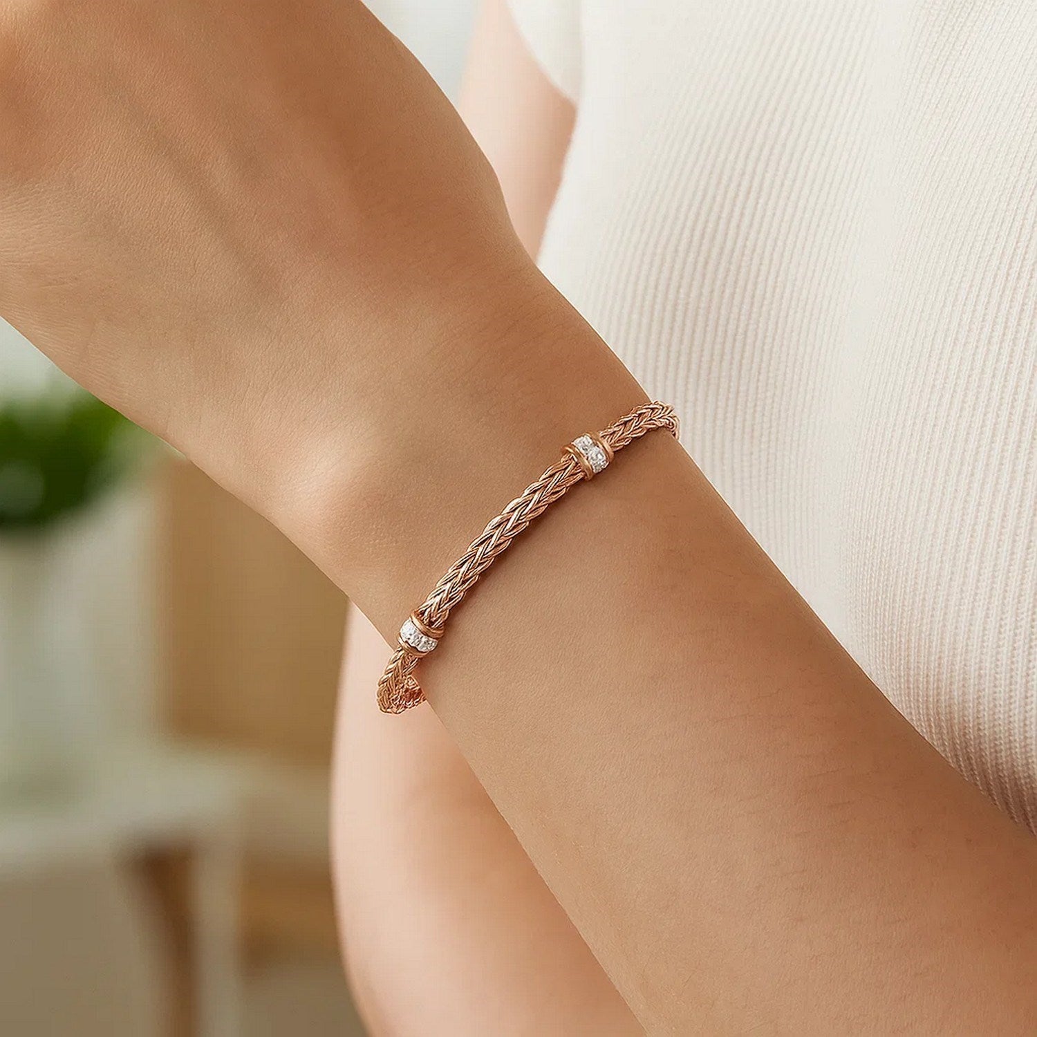 Polished 14k rose gold woven rope bracelet featuring round diamonds in a modern prong setting.