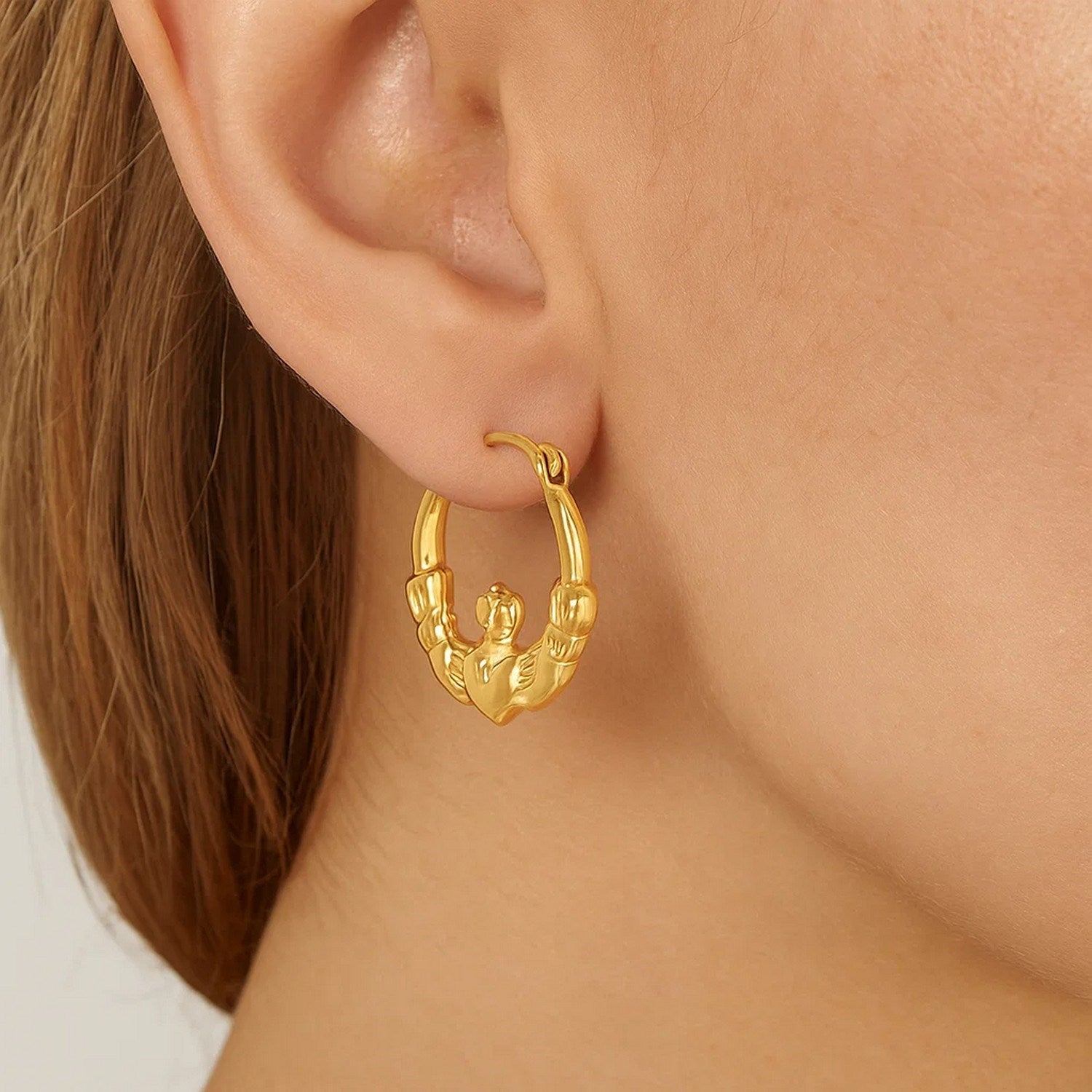 14k yellow gold Claddagh hoop earrings with modern oval design, symbolizing love and friendship.