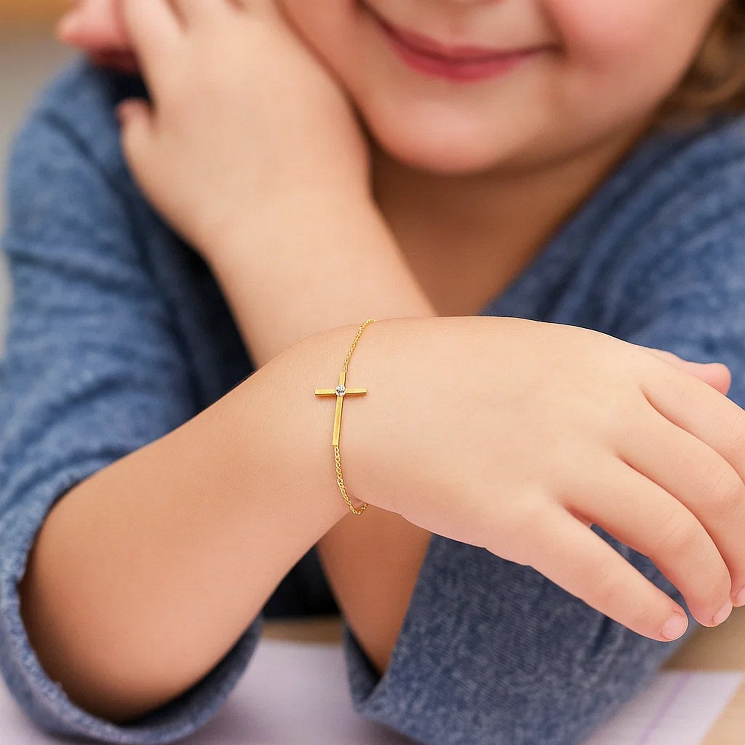 Elegant 14k yellow gold children's bracelet featuring a delicate cross design and fine chain detail.