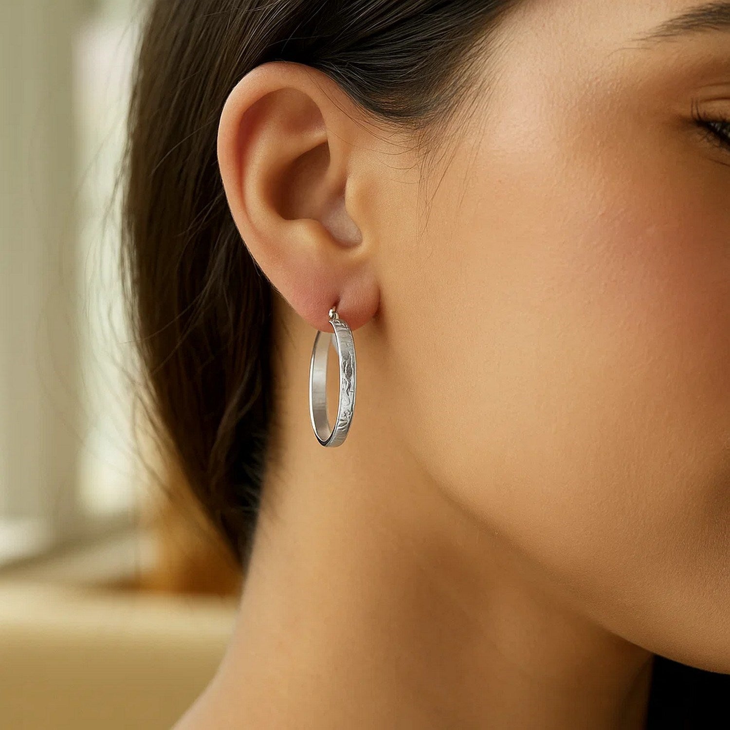Sterling silver hammered hoop earrings with rhodium plating, showcasing a modern design and elegant shine.