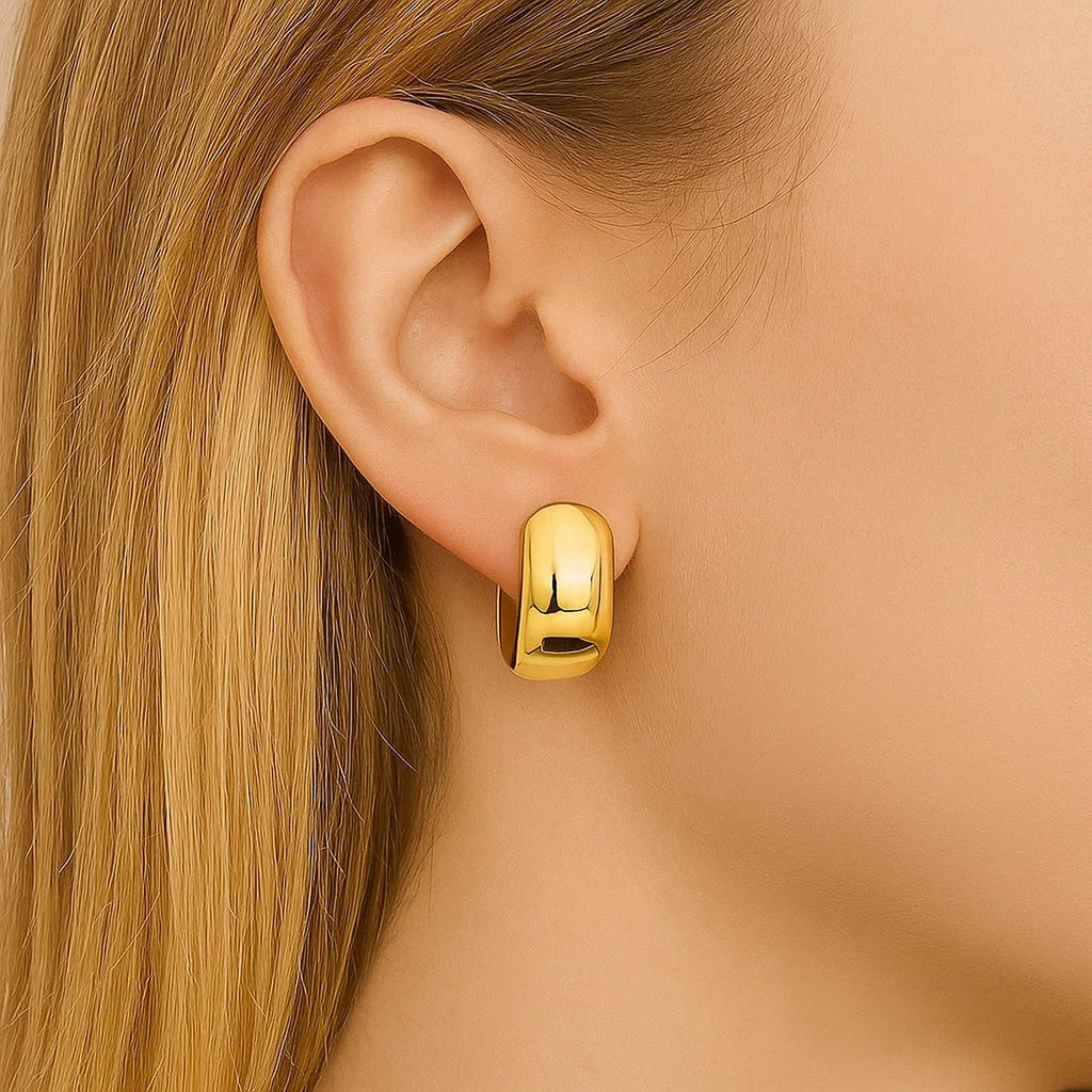 14K yellow gold polished huggie hoop earrings with a modern oval design, perfect for elegant everyday wear.