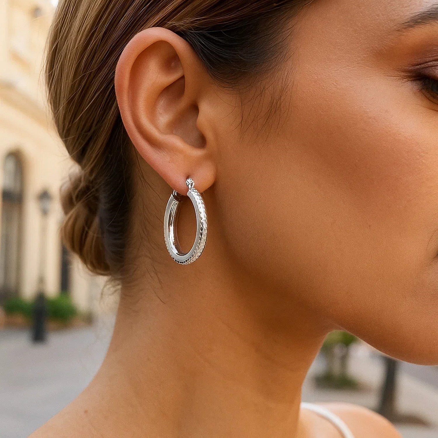 14k white gold textured hoop earrings featuring a modern oval design and sparkling diamond cut finish.