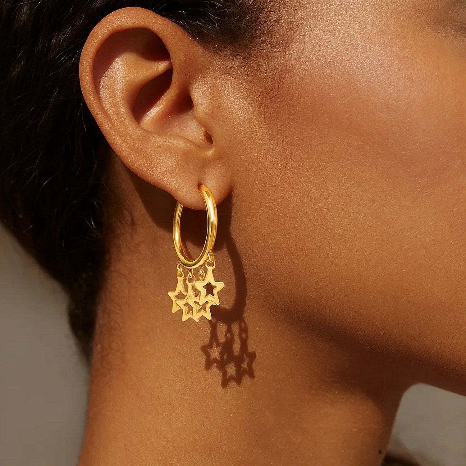 14K yellow gold huggie hoop earrings featuring an elegant endless star charm design for a luxurious touch.