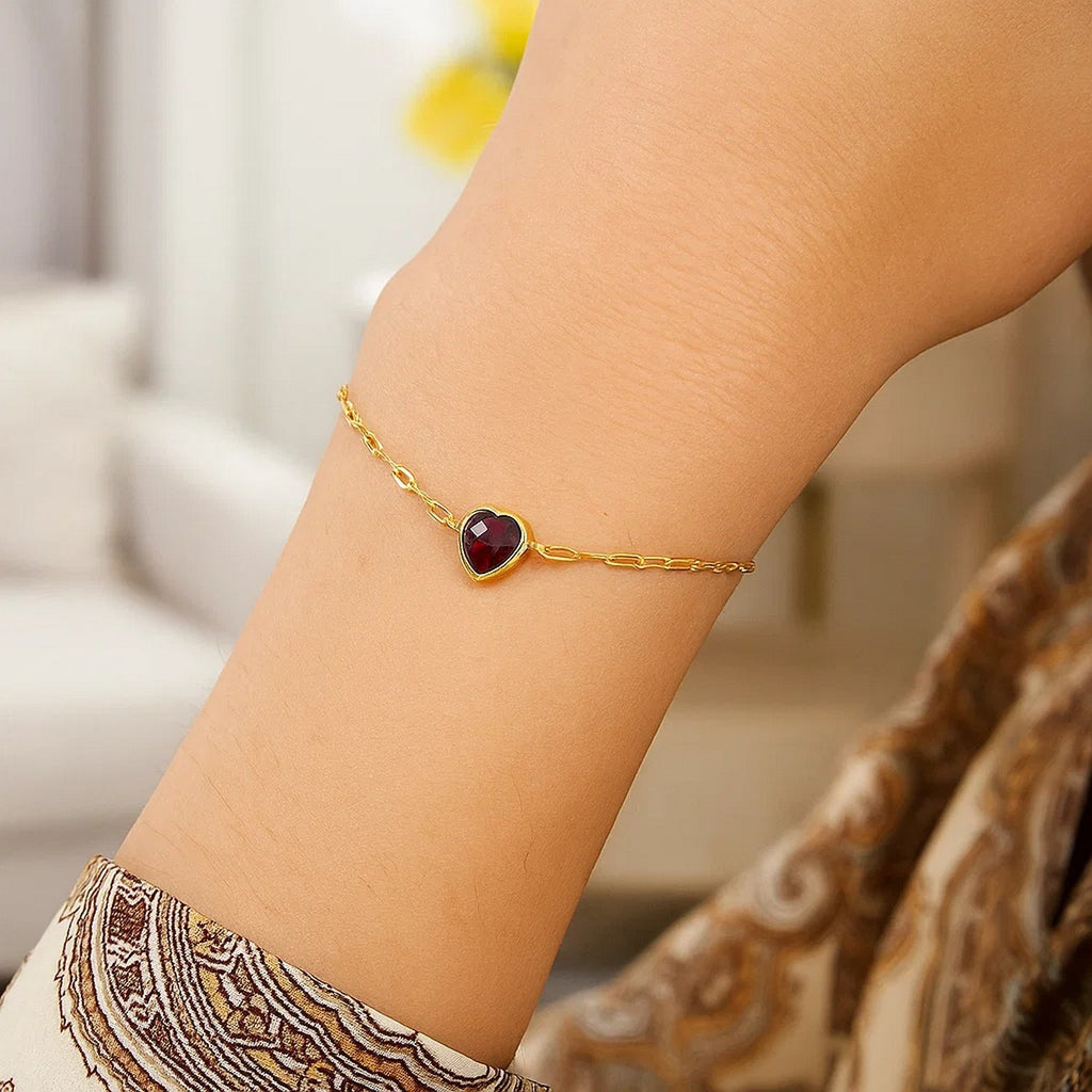 Elegant 14k yellow gold bracelet featuring a heart-shaped garnet on a delicate chain, perfect for luxury occasions.