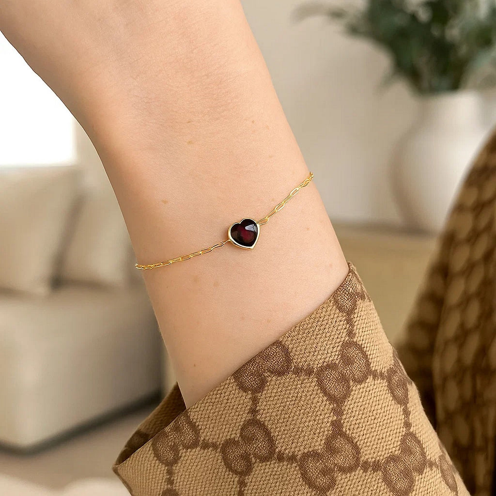 Elegant 14K yellow gold bracelet featuring a heart-shaped garnet on a delicate chain, perfect for any occasion.