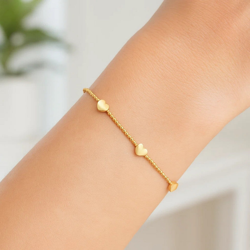 Elegant 14k yellow gold heart station bead bracelet showcasing luxurious design and timeless sophistication.