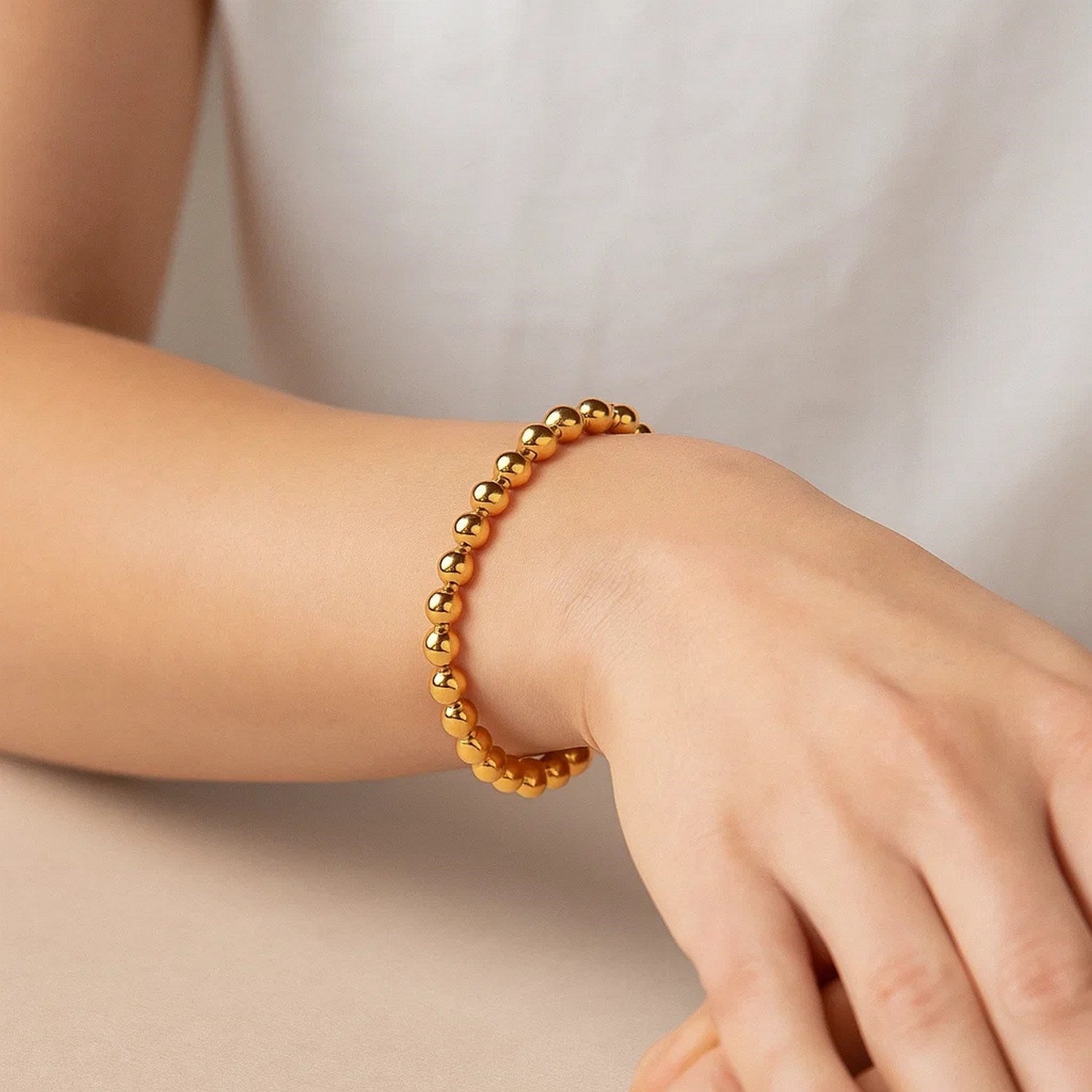 Polished 7mm bead bracelet in luxurious 14k yellow gold, showcasing minimalist elegance and timeless sophistication.