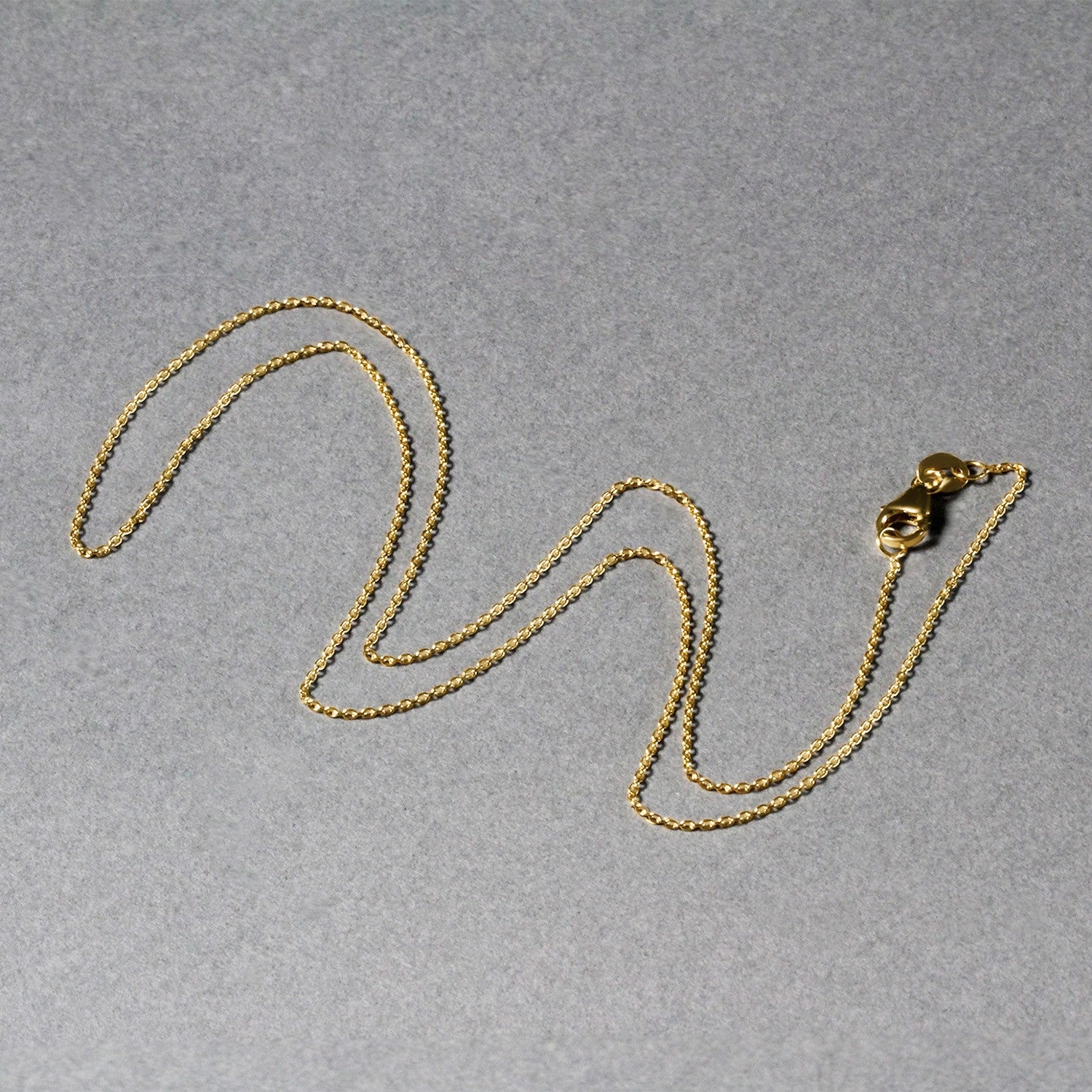 Elegant 18k yellow gold round cable link chain, showcasing a refined design with a lustrous finish.